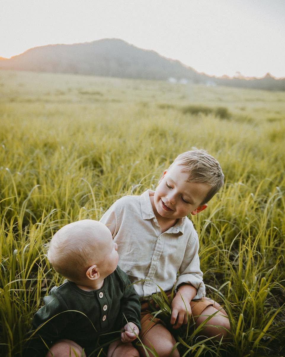 Brothers sitting together in the grass, smiling
