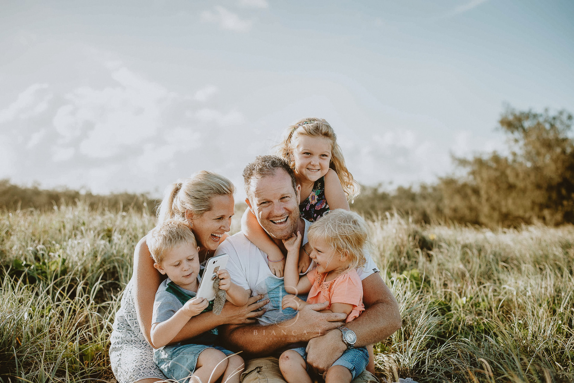Family laughing together in the dune grass