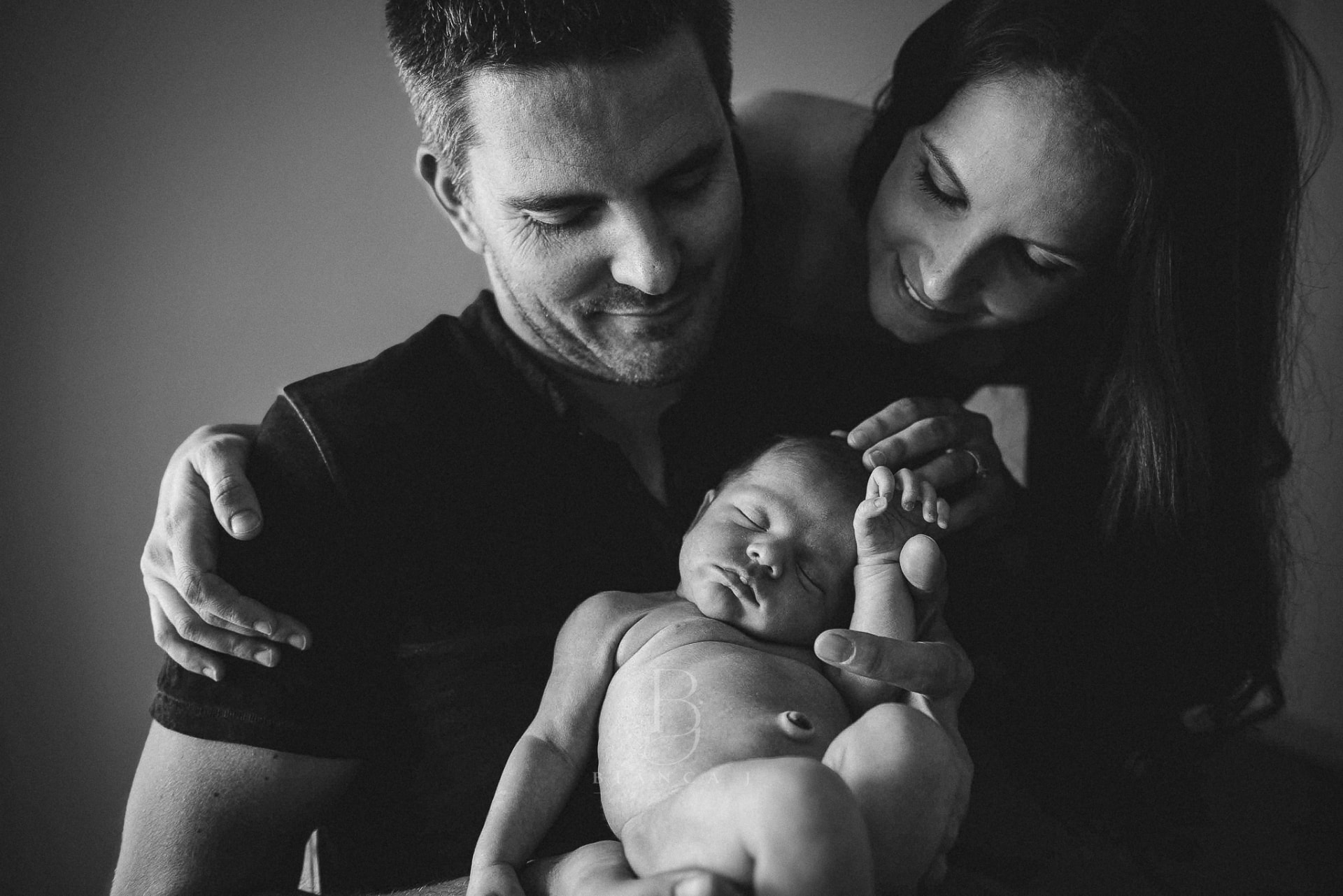 Mum and dad gazing down at their sleeping newborn